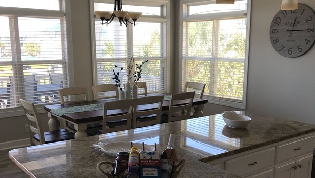A kitchen with a large island, white cabinetry, and pendant lighting.