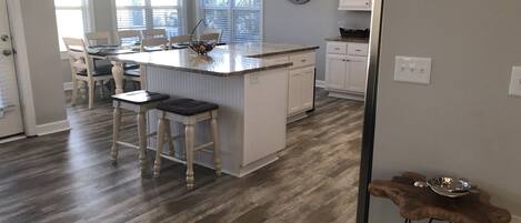 A kitchen with a central island, pendant lighting, and a clock on the wall.
