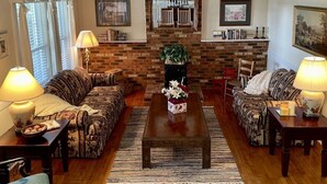 Ein Wohnzimmer mit zwei Sofas, einem Couchtisch und einem Kamin an einer Ziegelwand.