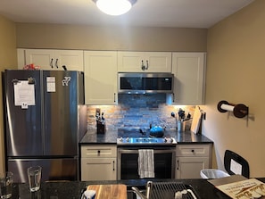 Una cocina equipada con refrigerador, microondas, estufa y hervidor.