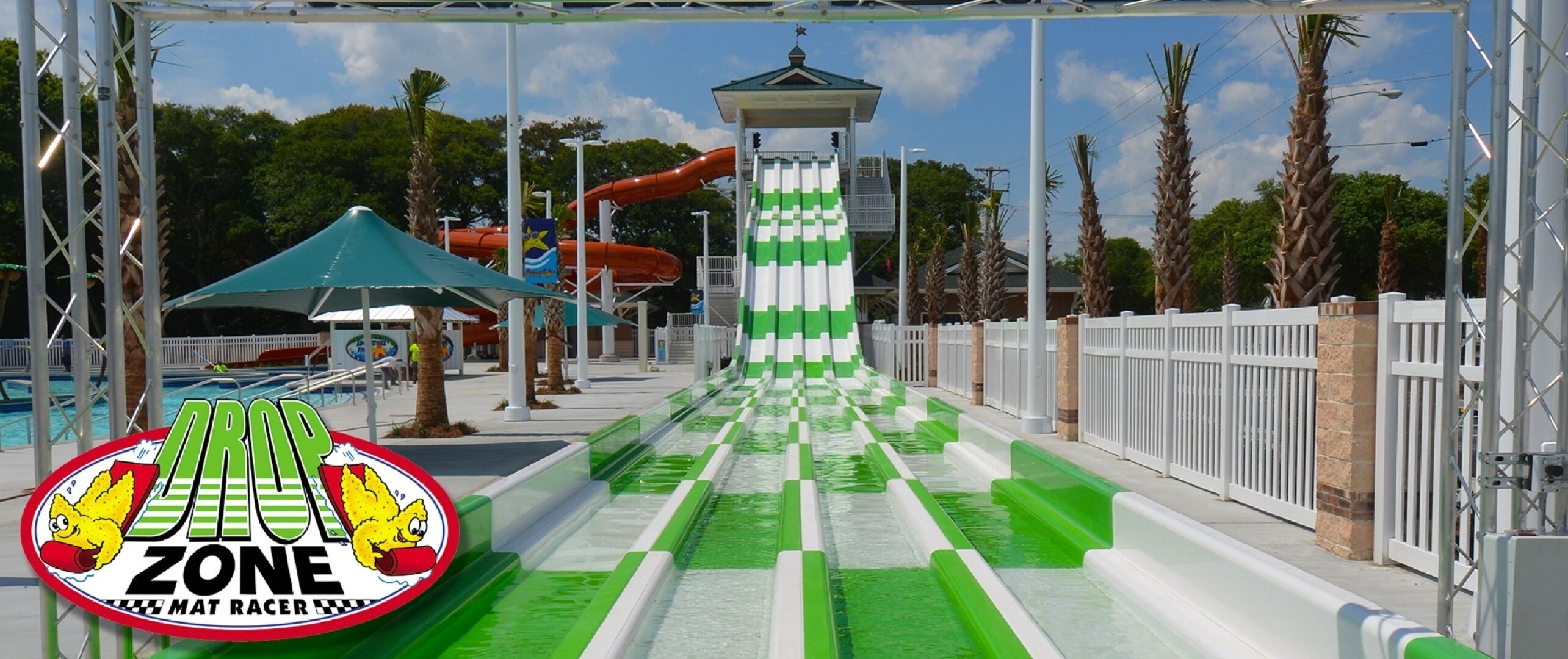 Ein Wasserpark mit einer grün-weißen und einer roten Wasserrutsche sowie einem kleinen Pavillon.