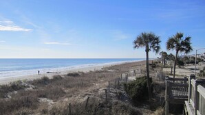 A beach with a wooden fence, palm trees, and a clear sky. - LAKEFRONT, 5 BDRM, Ocean View! Quiet. Fish off deck. Just reduced Aug wks! (Myrtle Beach)