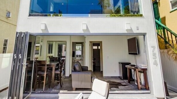 A modern two-story house with a balcony, a dining area, and a visible kitchen.