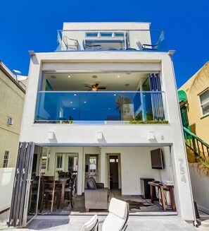 A modern two-story house with a balcony, a dining area, and a visible kitchen.