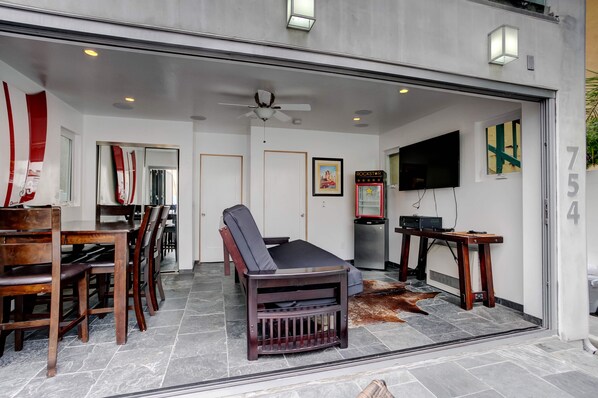 A modern interior with a dining area, a lounge with a sofa, a flat-screen TV, and a jukebox.