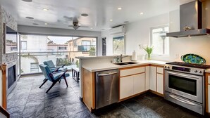 A modern kitchen with a dishwasher, oven, and a large window overlooking a residential area.