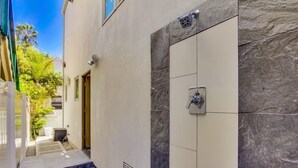 A modern bathroom with a shower, tiled walls, and a small outdoor area with steps leading to a door.
