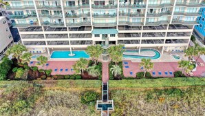 Un hôtel à plusieurs étages doté de balcons, d’une piscine et d’une cour aménagée.