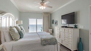 A bedroom with a bed, a dresser, a television, and a ceiling fan.