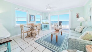 A room with a dining area, a sofa, and a view of the ocean.