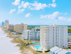 Un hôtel situé en bord de mer, composé de plusieurs immeubles de grande hauteur, doté d’une piscine et d’une zone de plage.
