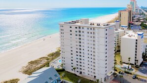 A high-rise hotel with multiple floors, a pool, and a beach view.