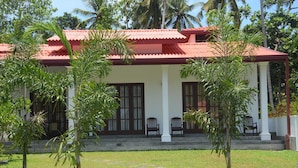 A building with a red roof, white columns, and a covered porch with two chairs. - Sithi Villas (Hikkaduwa)