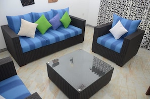 A living room with a blue-striped sofa, two armchairs, and a glass coffee table. - Sithi Villas (Hikkaduwa)