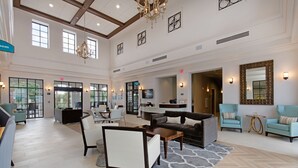 A spacious lobby with a reception desk, seating area, and a chandelier.