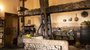 Un intérieur rustique avec des poutres apparentes, des murs en pierre et des étagères remplies de bouteilles et de bocaux.