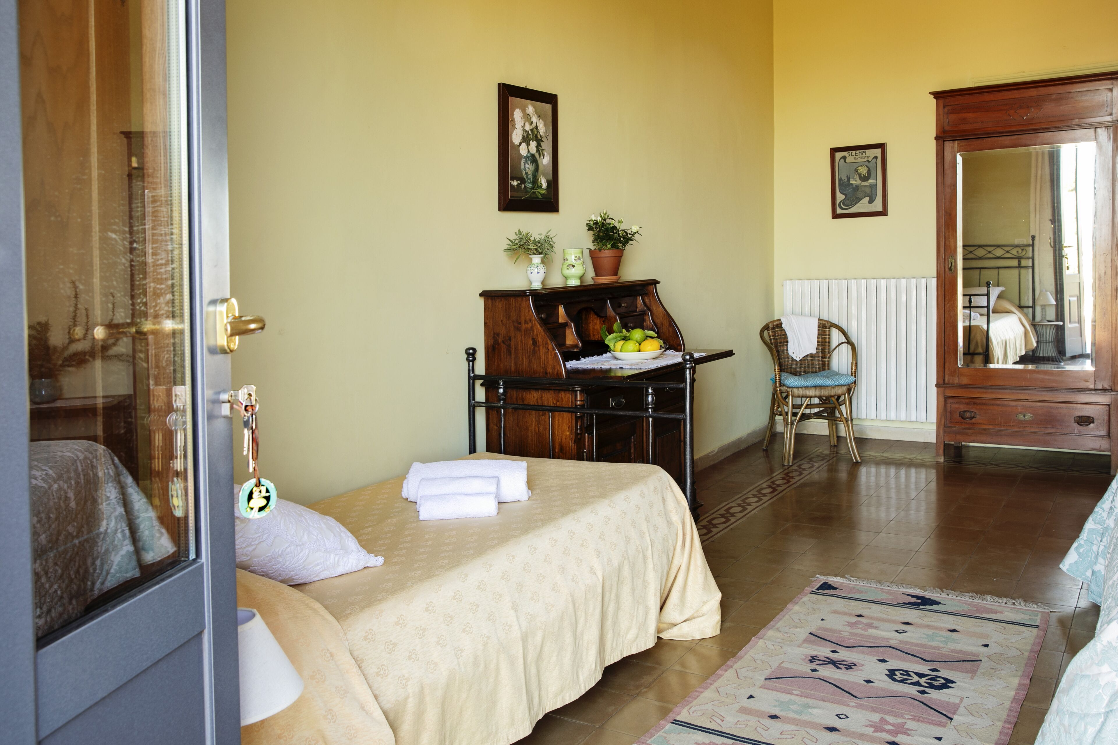 Une chambre à coucher avec un lit, une commode en bois, une chaise et un miroir.
