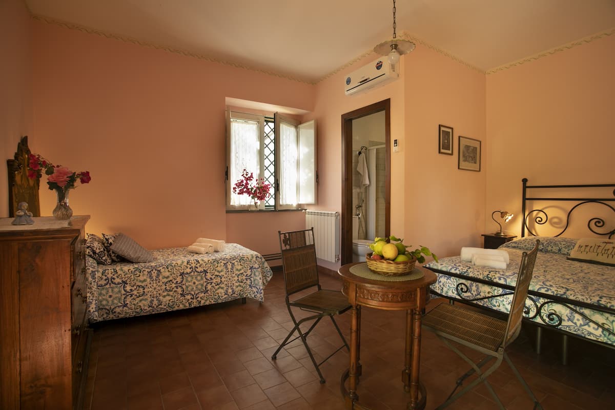 Un dormitorio con dos camas, una mesita con fruta, una silla y un aparador.