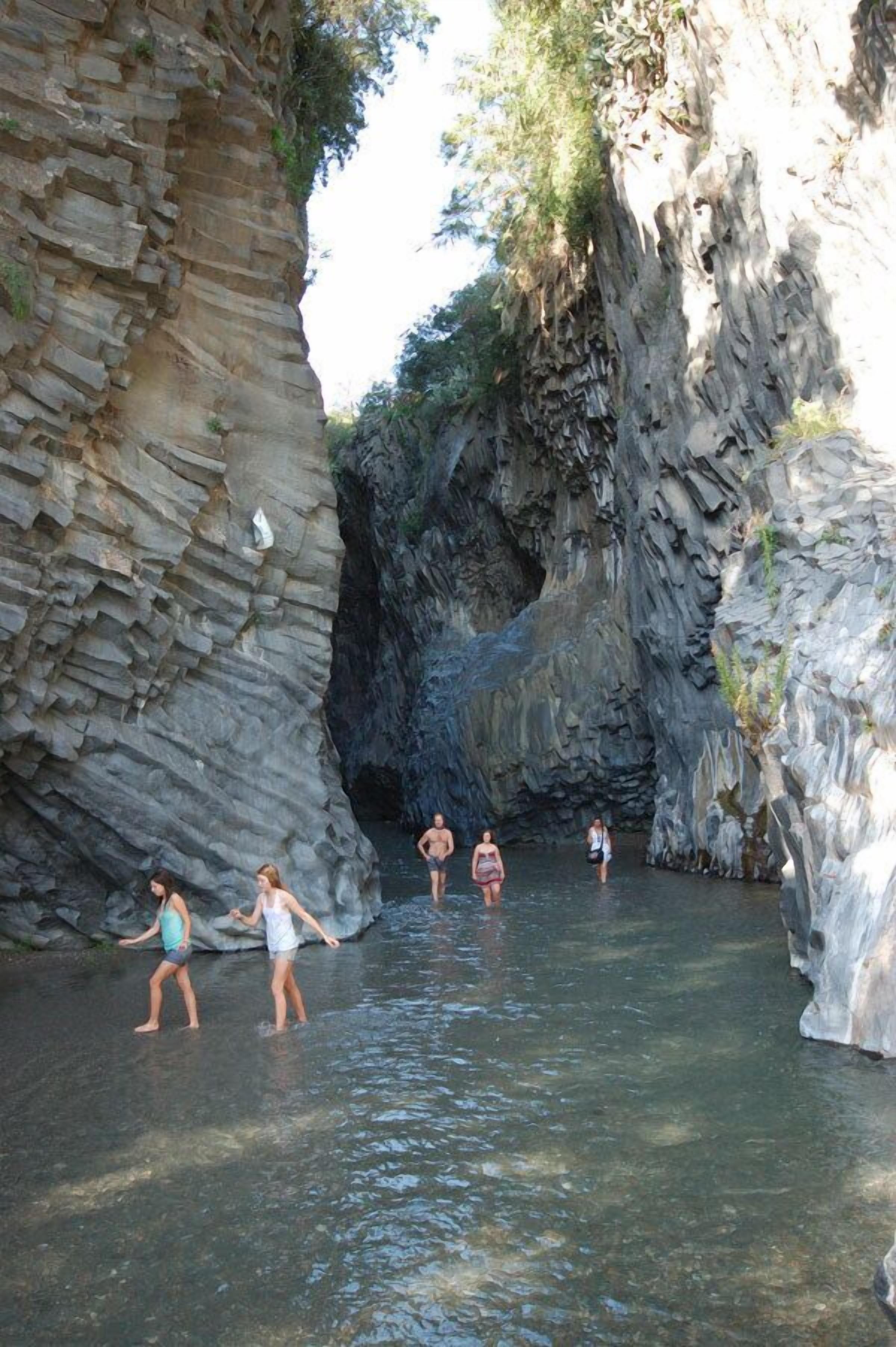 Une formation rocheuse naturelle avec de l’eau claire, entourée de végétation.