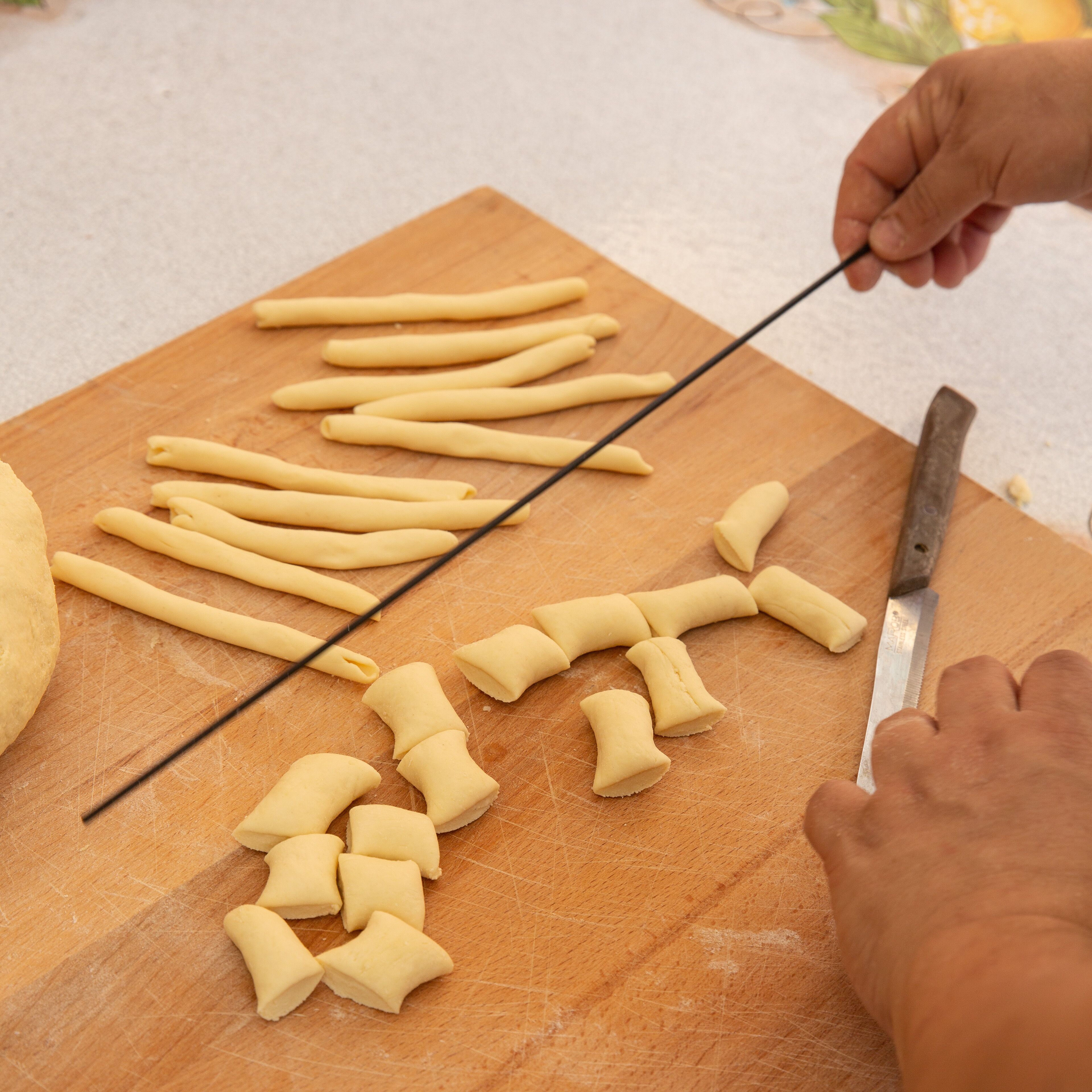 Una persona che taglia pasta su un tagliere di legno.