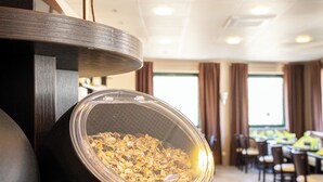 A breakfast buffet setup with a bowl of cereal, wooden spoons, and a sign that reads "Misti". - Hotel Aulmann (Trier)