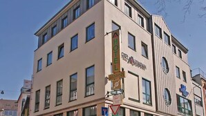 A multi-story hotel with a modern facade, large windows, and a visible sign indicating hotel services. - Hotel Aulmann (Trier)