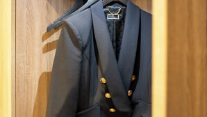 A wooden closet with three dark-colored blazers hanging on black hangers. - Hotel Aulmann (Trier)