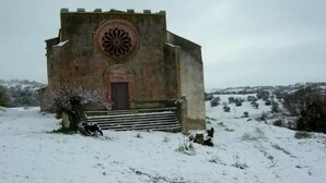 Un petit bâtiment en pierre, doté d’une fenêtre circulaire et d’une porte, entouré d’un sol enneigé et d’une végétation clairsemée.
