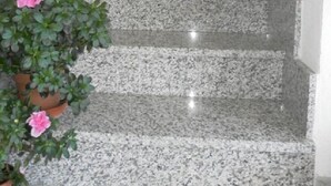 Un escalier en granit, avec des plantes en pot disposées sur les marches.