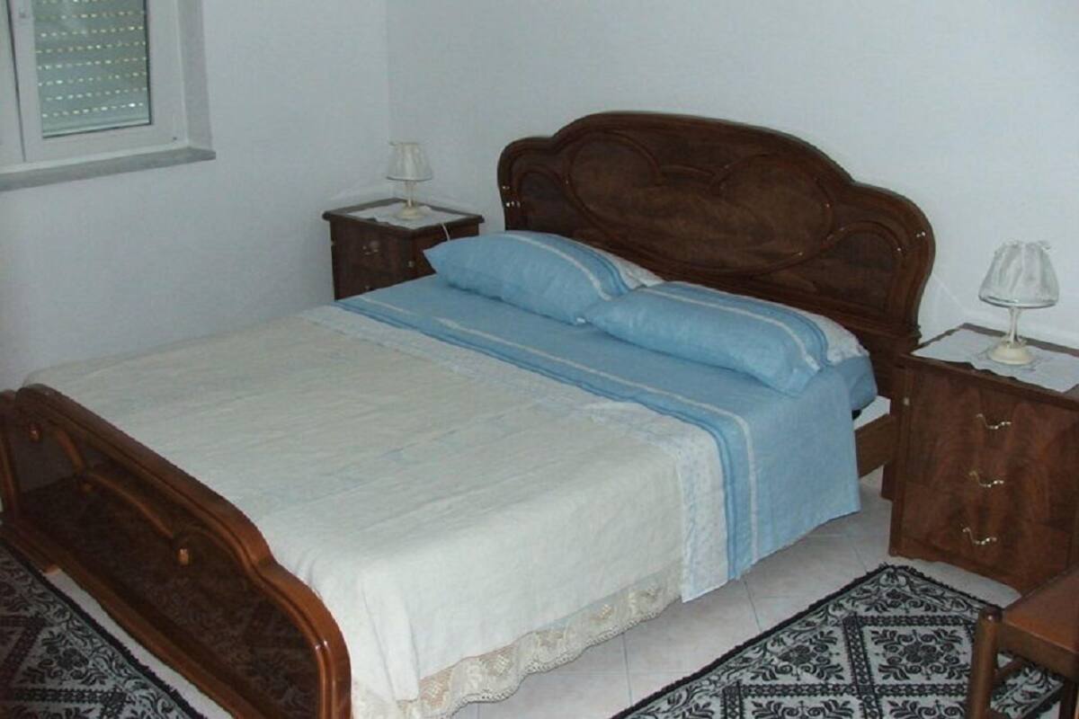 Ein Schlafzimmer mit einem hölzernen Bett, einem Nachttisch, einer Lampe und einem gemusterten Teppich.
