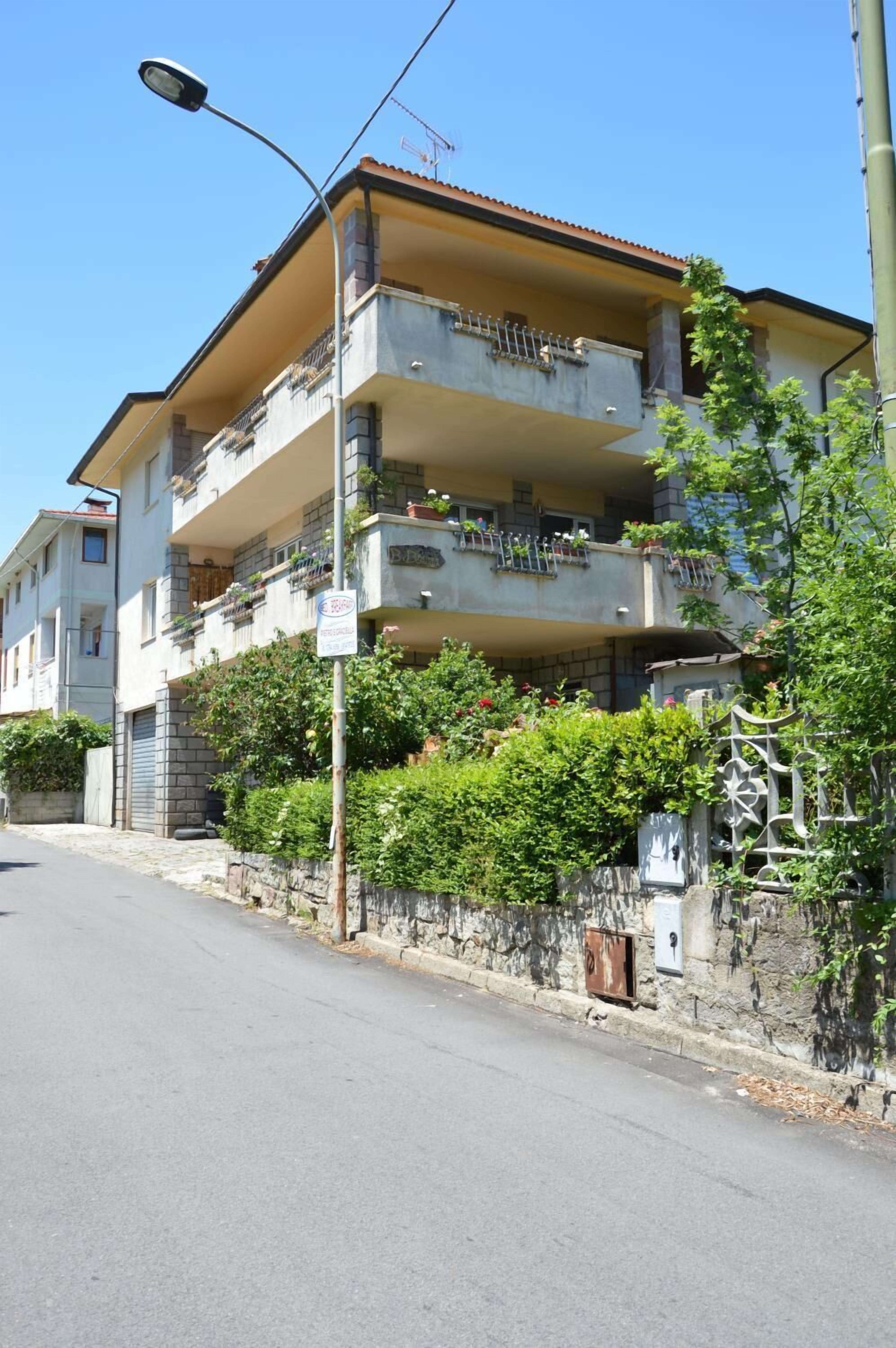 Un edificio residencial de varios pisos con balcones, una farola y un cielo despejado.