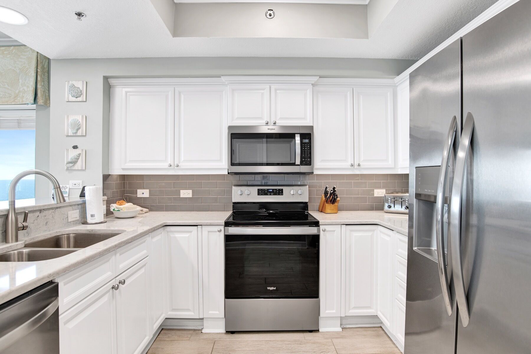 Una cocina moderna con armarios blancos, electrodomésticos de acero inoxidable y salpicadero de azulejos.