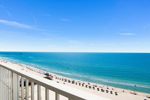 A beach with a long stretch of sand, a pier in the distance, and a clear blue sky. - Seawind 1309 | Updated condo with perfect beach view and walk to dine, shop, more! (Gulf Shores)