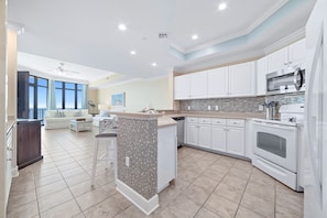 A modern kitchen with white cabinets, a tiled backsplash, and a central island.