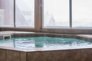 Un jacuzzi con vista a un paisaje nevado a través de amplias ventanas.