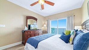 Une chambre à coucher avec un lit, un ventilateur de plafond, une commode, un miroir et une fenêtre donnant sur un beau paysage.