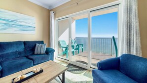 Un balcon avec vue sur l’océan, un canapé bleu et une table basse en bois.