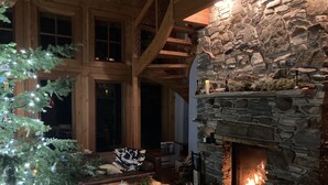 Un interior acogedor con chimenea de piedra, vigas de madera, un árbol de Navidad y un espacio de descanso cómodo.