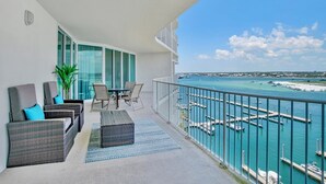 Un balcón con mobiliario exterior, vista a un puerto deportivo y cielo despejado.