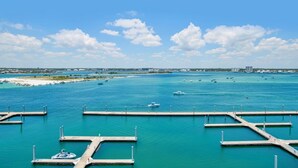 Una marina con varios muelles y barcos, un cielo azul despejado y una costa distante con edificios.