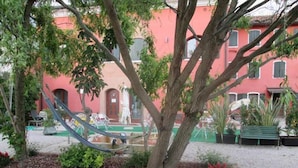 Une cour avec un hamac, un banc et un bâtiment à la façade rouge.