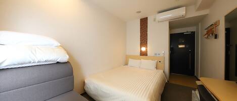 A hotel room with a bed, a desk, and a wardrobe.