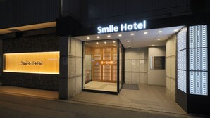 Exterior del Hotel Smile con fachada moderna, una entrada destacada y un letrero que indica el camino al vestíbulo 2F.