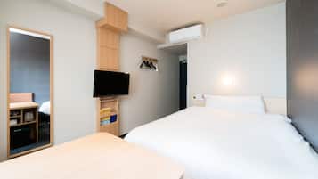 A hotel room with a bed, a desk, a TV mounted on the wall, and a wardrobe.