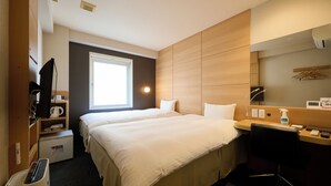 Habitación de hotel con una cama grande, un escritorio con silla, televisor, microondas y ventana que proporciona luz natural.