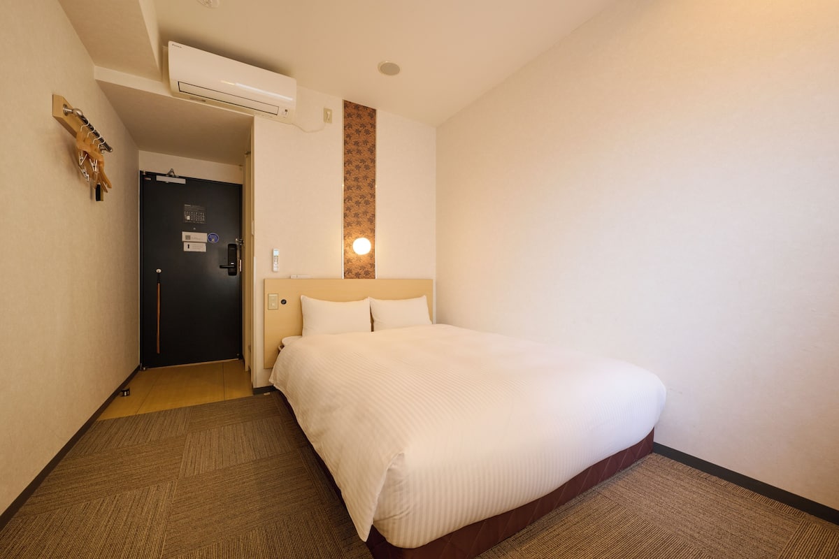 Een hotelkamer met een bed, een deur en een wandairconditioner.