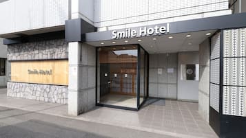 Exterior del Hotel Smile, con fachada de piedra, letrero de madera y entrada de cristal.
