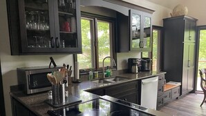 Una cocina moderna con armarios oscuros, estufa integrada y un ventanal que proporciona luz natural.