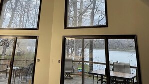 Una habitación con ventanas amplias que dan vistas a un lago y árboles.
