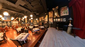 Un restaurante con mesas dispuestas para comer, un piano y obras de arte en las paredes.